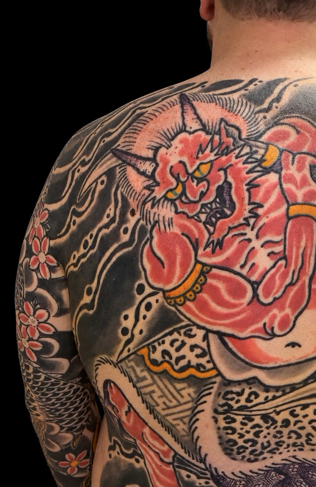 Colourful Japanese backpiece with oni and swirling clouds on a solid black background