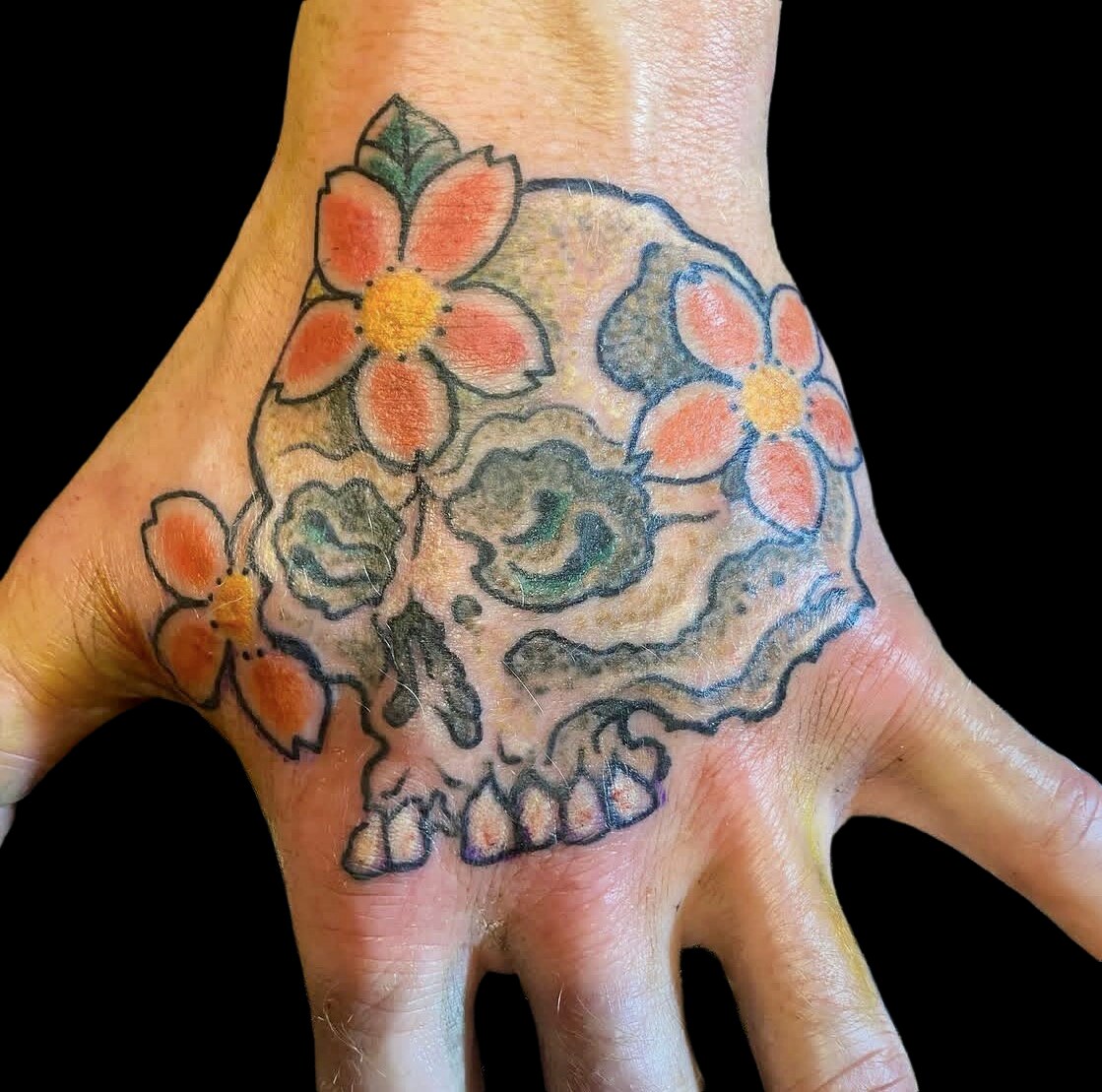 Skull and cherry blossom hand tattoo