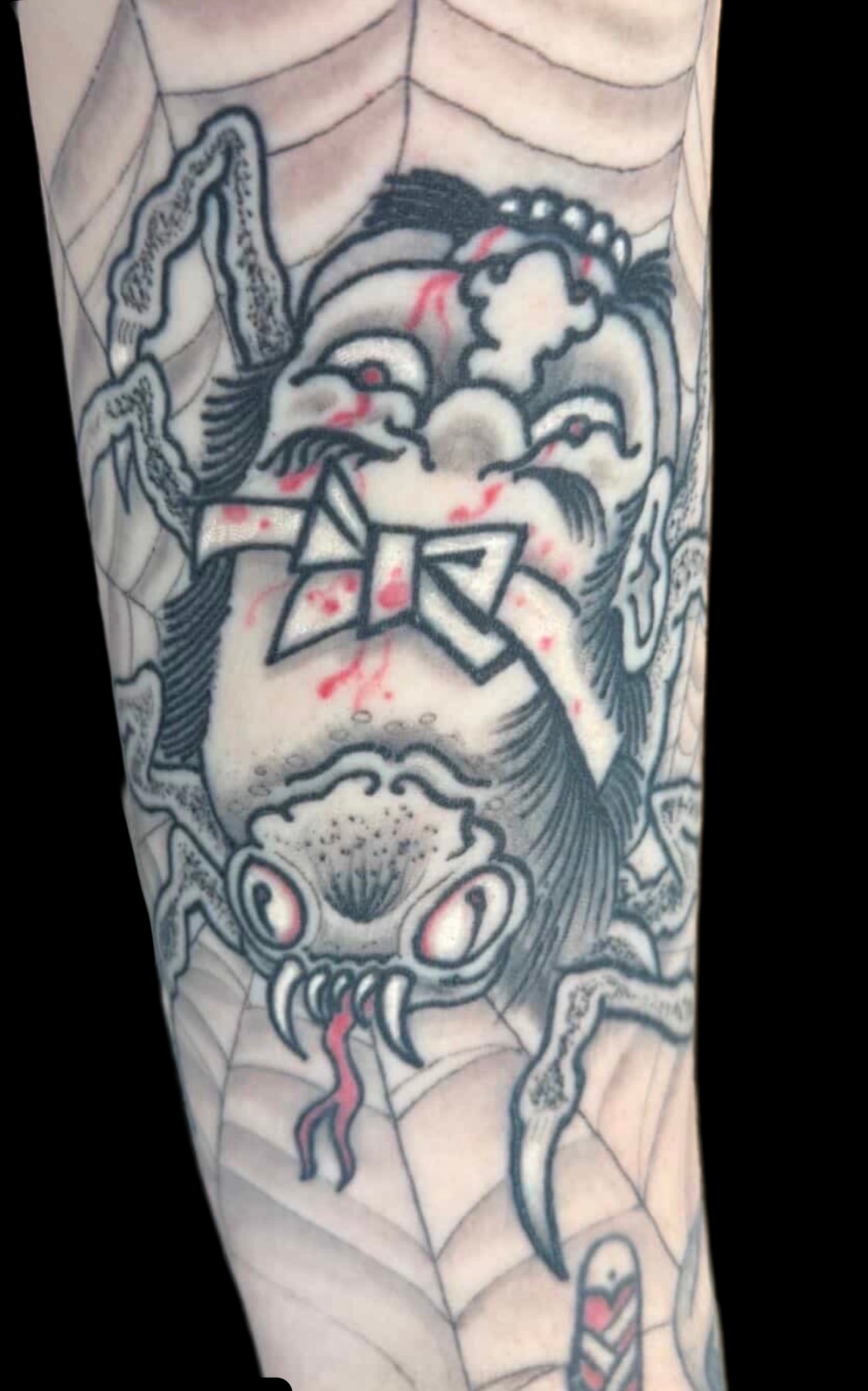 Black and red Japanese namakubi and spider tattoo on a solid black background
