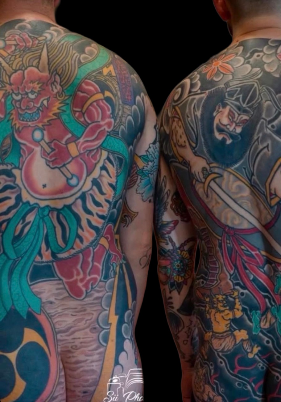 Two completed Japanese bodysuit backpieces on a solid black background