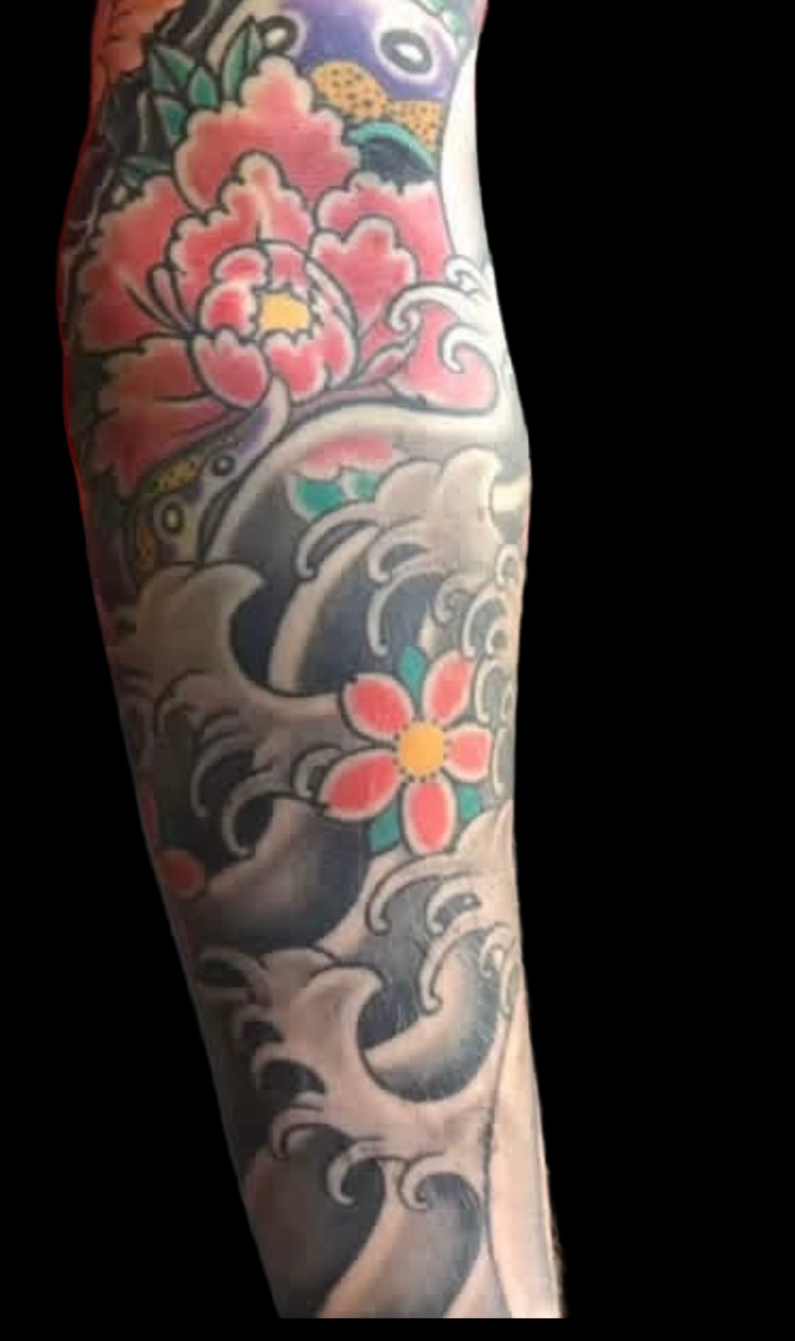 Colour peony and Japanese wave sleeve tattoo on a solid black background